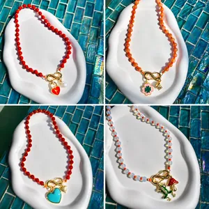 Ensemble de colliers de perles colorés avec pendentifs cœur et fleurs sur plat blanc