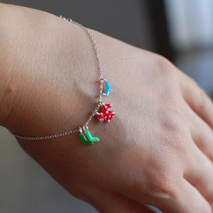 Silver charm bracelet with colorful enamel dog and boot pendants on a model's wrist
