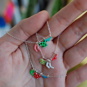 Macro shot of silver necklace with colorful enamel clothes and socks charms