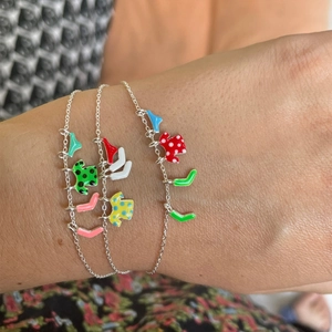 Detailed view of three silver chains featuring colorful enamel clothes and boots charms