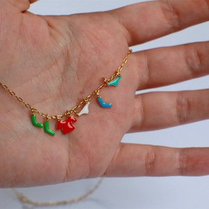 Macro shot of gold necklace featuring colorful enamel clothing and sock charms