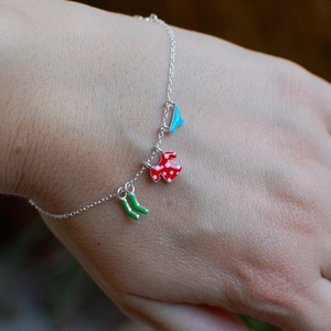 Close-up of silver chain bracelet with colorful enamel laundry-themed charms on wrist