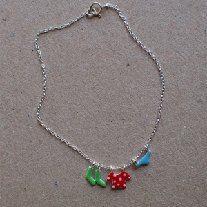 Detailed macro view of silver chain featuring colorful enamel charms with playful clothing motifs