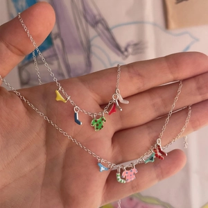 Detail of creative double silver chains featuring colorful enamel clothes-shaped pendants