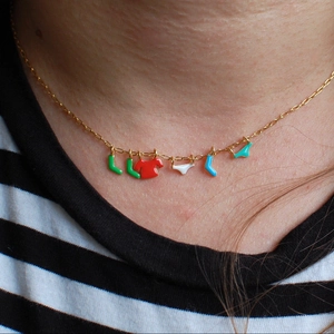 Quirky gold necklace with colorful enamel laundry charms on a striped shirt model