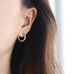 Gros plan d'une créole épaisse en argent sur l'oreille avec une finition polie miroir lisse