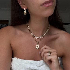 Primer plano de conjunto de joyas florales doradas con collar esmaltado y anillo a juego