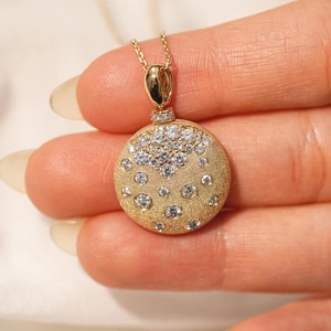 Primer plano del collar de relicario dorado con luna, estrellas y acabado mate
