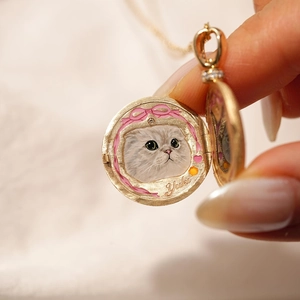 Detalle de relicario de oro abierto con retrato de gato pintado a mano y diamantes