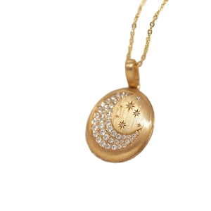 Collar de relicario con luna y estrella dorada, acabado en metal cepillado y circonitas