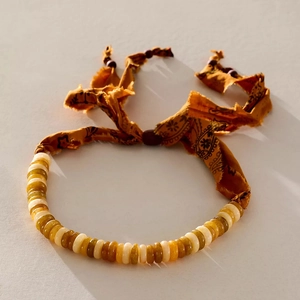 Detail van boho-parelketting met paisley stoffen lint en 18k vergulde accenten