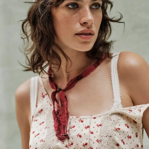 Detail van een bloemen crop top met kant en een dunne rode bedrukte sjaal om de nek