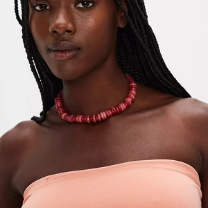 Detail van een boheemse choker-halsketting met rode en roze kralen op een model