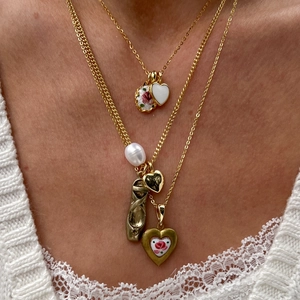 Detail of layered gold necklaces with baroque pearl, ballet shoes, and heart pendants
