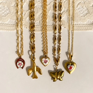 Vintage gold necklaces collection featuring heart, butterfly, and rose charms on a lace background