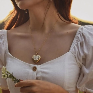 Collar de relicario vintage en forma de corazón con relieve de rosa y luz de ocaso