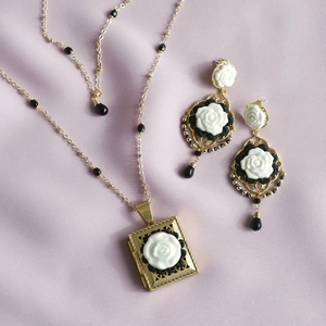Detalle del conjunto de collar con relicario dorado vintage y pendientes con rosa