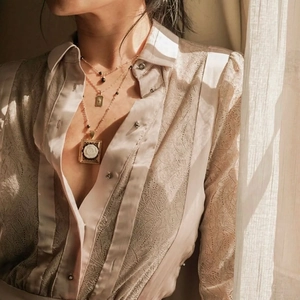 Detalle de collar dorado de tres capas con camafeo de rosa y colgante de placa en modelo