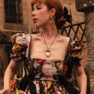 Primer plano de collar con relicario vintage y pendientes barrocos con vestido