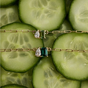 Detalle de cadena dorada con circonitas en forma de gota y piedras verdes