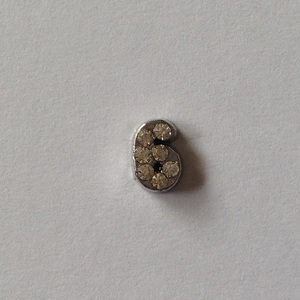 Détail d'un accessoire pendentif chiffre 6 en argent orné de strass brillants sertis