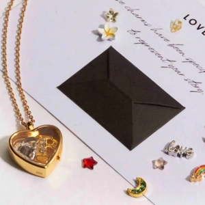 Gold heart-shaped locket necklace with transparent window and colorful floating charms