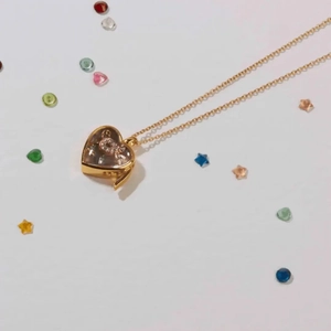 Collana con pendente a medaglione a cuore dorato vintage con cristalli su sfondo bianco