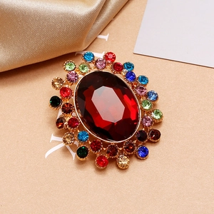 Détail d'une broche de luxe avec pierre rouge ovale et strass multicolores sur métal doré