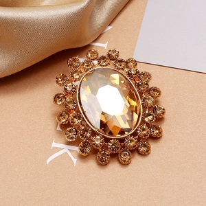 Détail de la broche vintage dorée avec cristal ambré et entourage de strass brillants