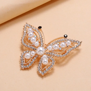 Elegant gold butterfly brooch featuring inlaid pearls and sparkling crystals on beige base