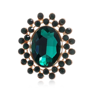 Vue détaillée de la broche luxueuse avec strass émeraude ovale et cristaux vert doré