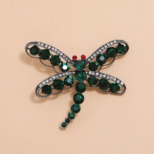 Détail de la broche libellule ornée de cristaux vert émeraude et de strass rouges aux yeux