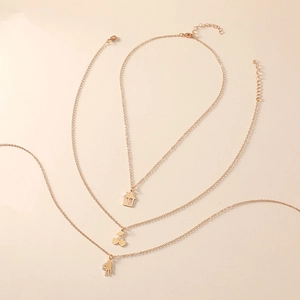 Parure de trois colliers dorés avec pendentifs maison, cerise et geste de la main OK