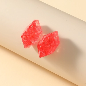 Macro shot of geometric red resin earrings with shimmering botanical floral textures