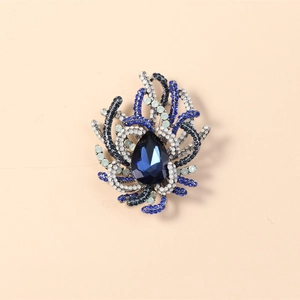 Detailed close-up of a blue pear-shaped crystal brooch with sparkling rhinestones