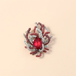 Detailed macro view of a vintage crystal brooch with a red teardrop stone and gold base