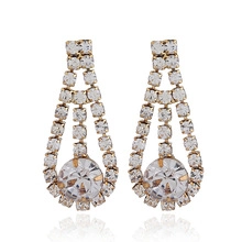 Detail of gold tassel earrings with hollow teardrop design and sparkling rhinestones