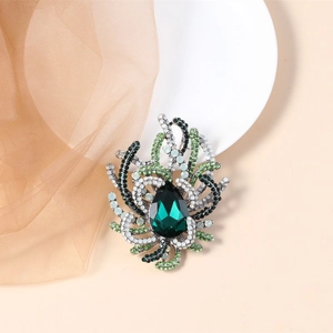 Detail of vintage emerald crystal brooch with intricate rhinestone and bead setting