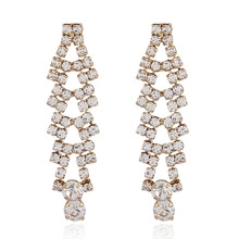 Detail showing long gold tassel earrings with sparkling rhinestones and clear crystals