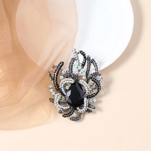 Close-up of elegant black water-drop zircon brooch with sparkling rhinestones on fabric