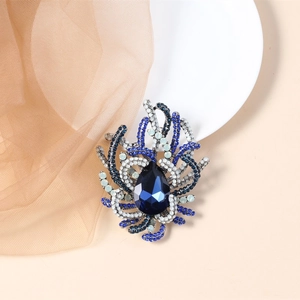 Macro detail of large blue teardrop gemstone brooch with crystal coral motifs