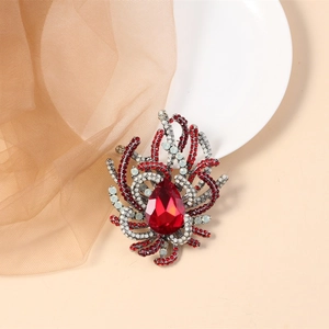 Close-up of a vintage crystal brooch with a red pear-shaped stone and rhinestones