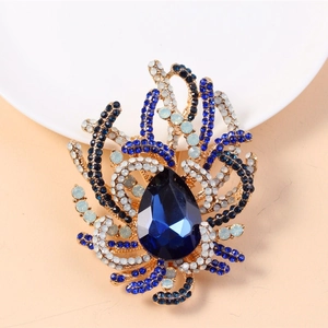 Macro shot of vintage gold brooch with blue crystals and a large teardrop gemstone