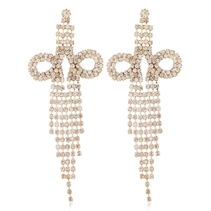 Detail of long gold tassel earrings with sparkling rhinestones in a butterfly bow shape