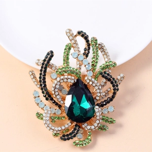 Macro shot of luxury vintage brooch with teardrop green crystal and gold-tone setting