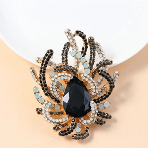 Detailed close-up of a vintage brooch with large black teardrop gem and gold branch accents
