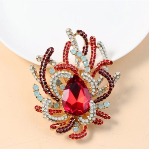 Detailed close-up of a vintage golden brooch with red teardrop stone and colorful rhinestones