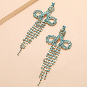 Detailed macro view of long tassel earrings with light blue crystals in gold setting