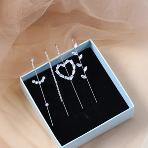 Set of four silver geometric drop earrings with crystals on a jewelry box display