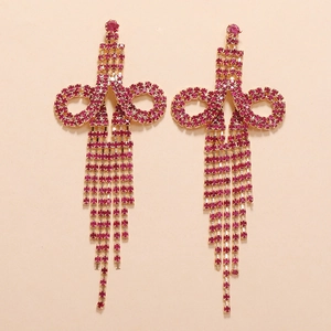 Detail of long gold earrings with rose pink rhinestones and swaying fringe tassels